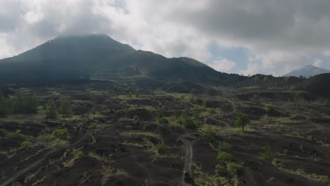 在巴圖爾山下面的黑色<unk>岩田, 一輛吉普車在沙路上行駛,