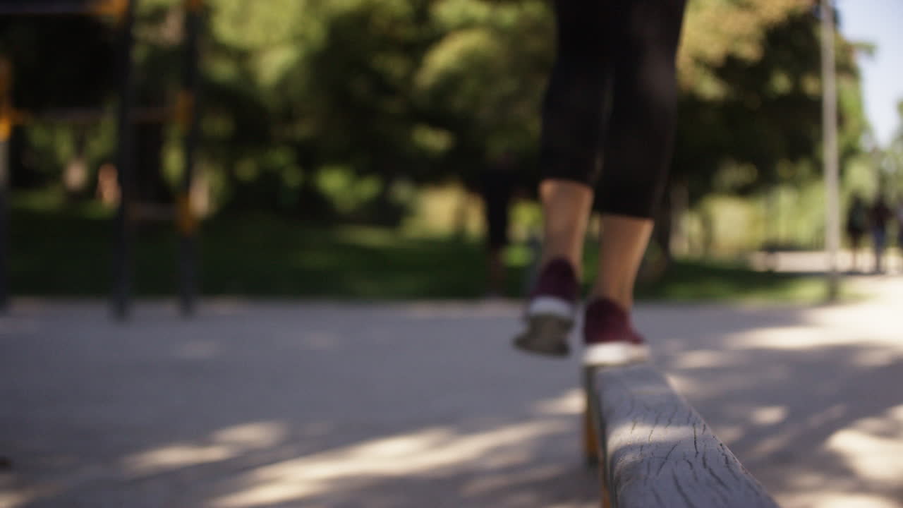 Young woman practices on a balance beam in a fitness park in Spain, close up