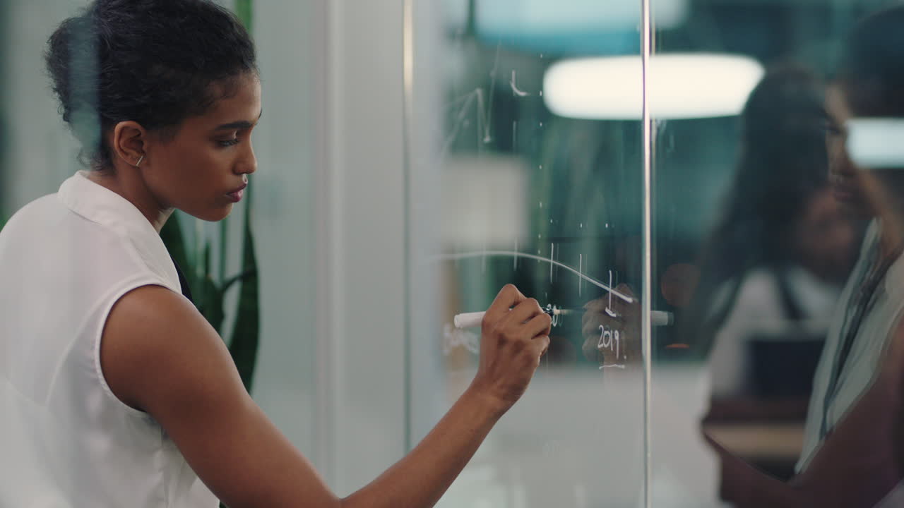 business woman writing on glass whiteboard female project manager brainstorming sales strategy using marketing data working late in office