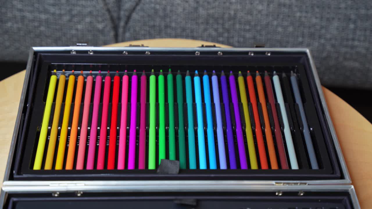 Closeup of a hand picking a red pencil from an organized box of colorful pencils. Symbolizes creativity, education, choice, and artistic expression