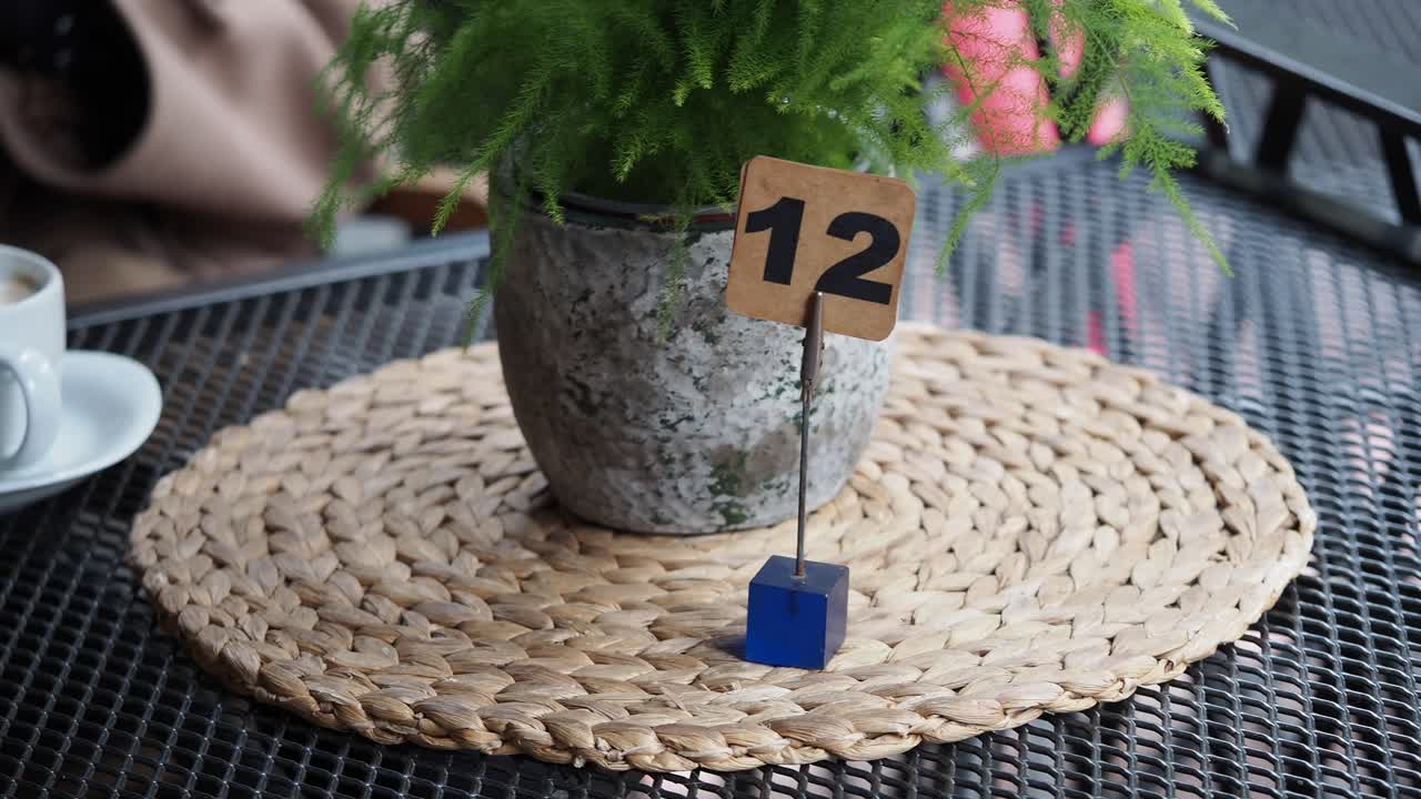 Tavolo da bar apparecchiato con il numero 12 e una pianta verde