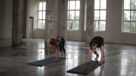 man and woman pushups at empty loft studio with columns. doing exercise synchronously. stylish people in sportwear with dreadlocks. sport, fitness and healthy lifestyle concept