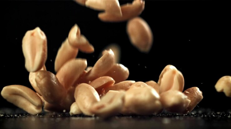 Raw Peanuts Falling in Slow Motion on a Black Background