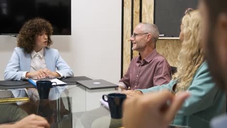 Happy mature businessman discussing with female colleagues during meeting