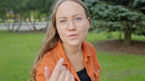 una rubia con gafas que expresa el deseo de comunicarse con el espectador