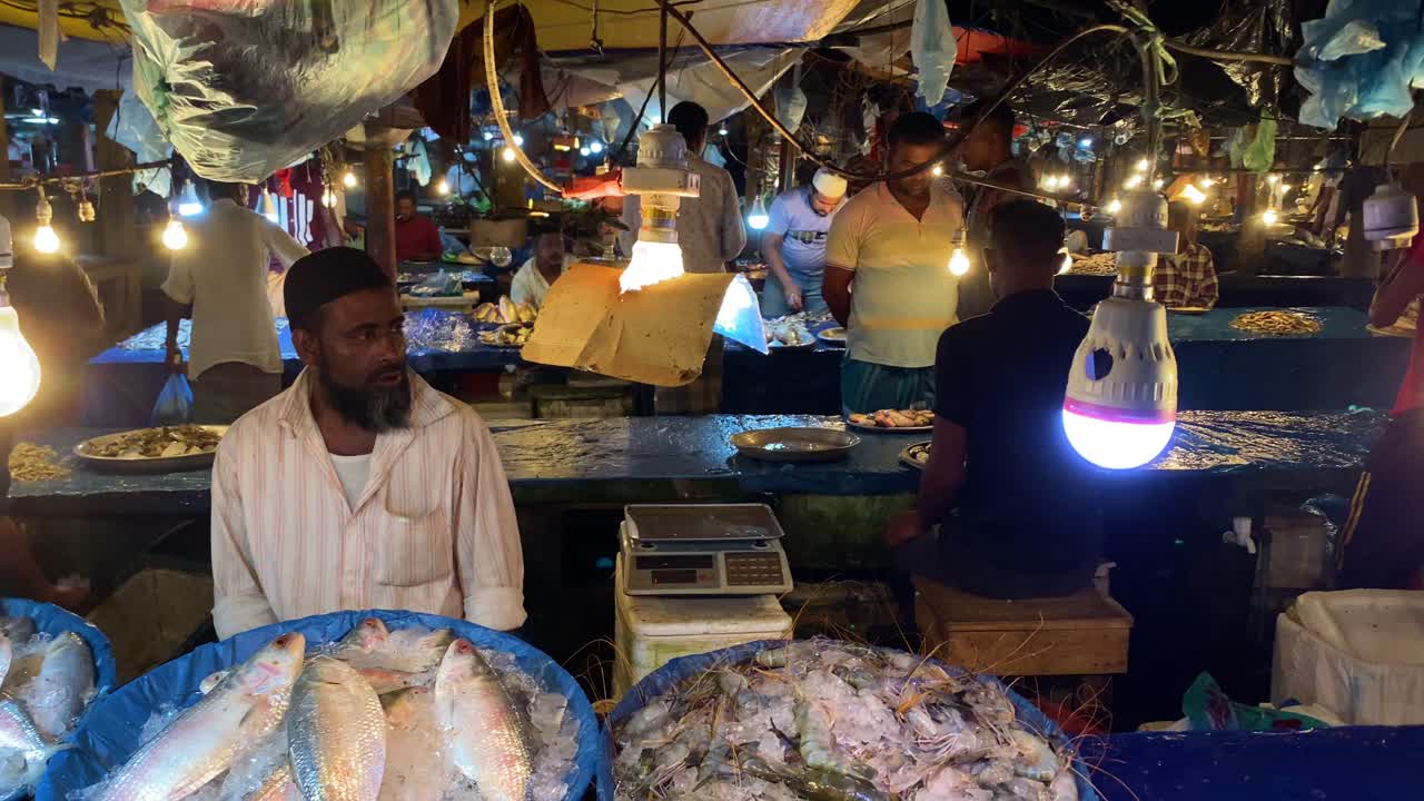 Vendors selling fresh fish covered with ice in an indoor solar powdered market, Bangladesh