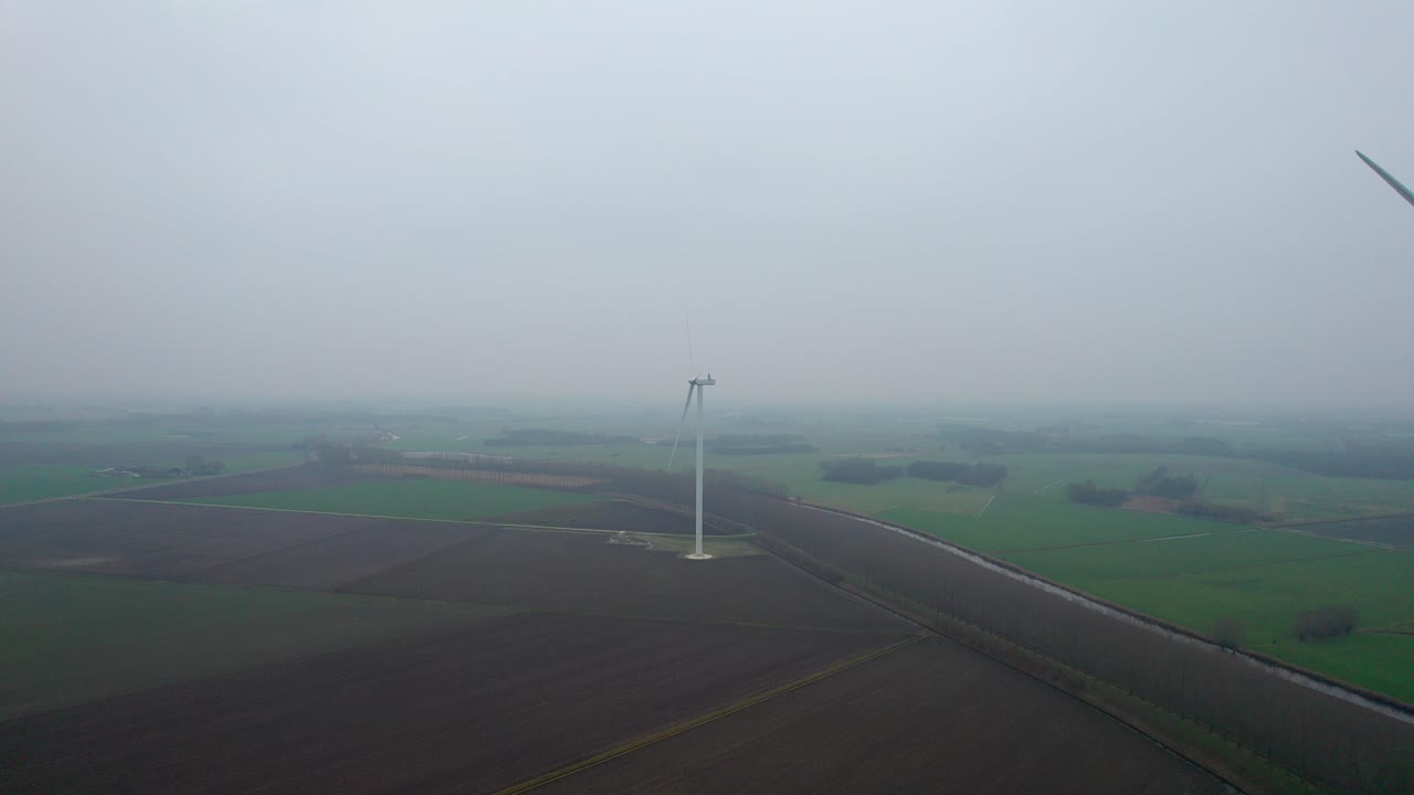 안개가 자욱한 네덜란드 풍경 속에서 회전하는 풍력 터빈을 향해 날아가는 드론
