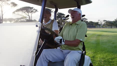 two golfers laughing together in their golf buggy