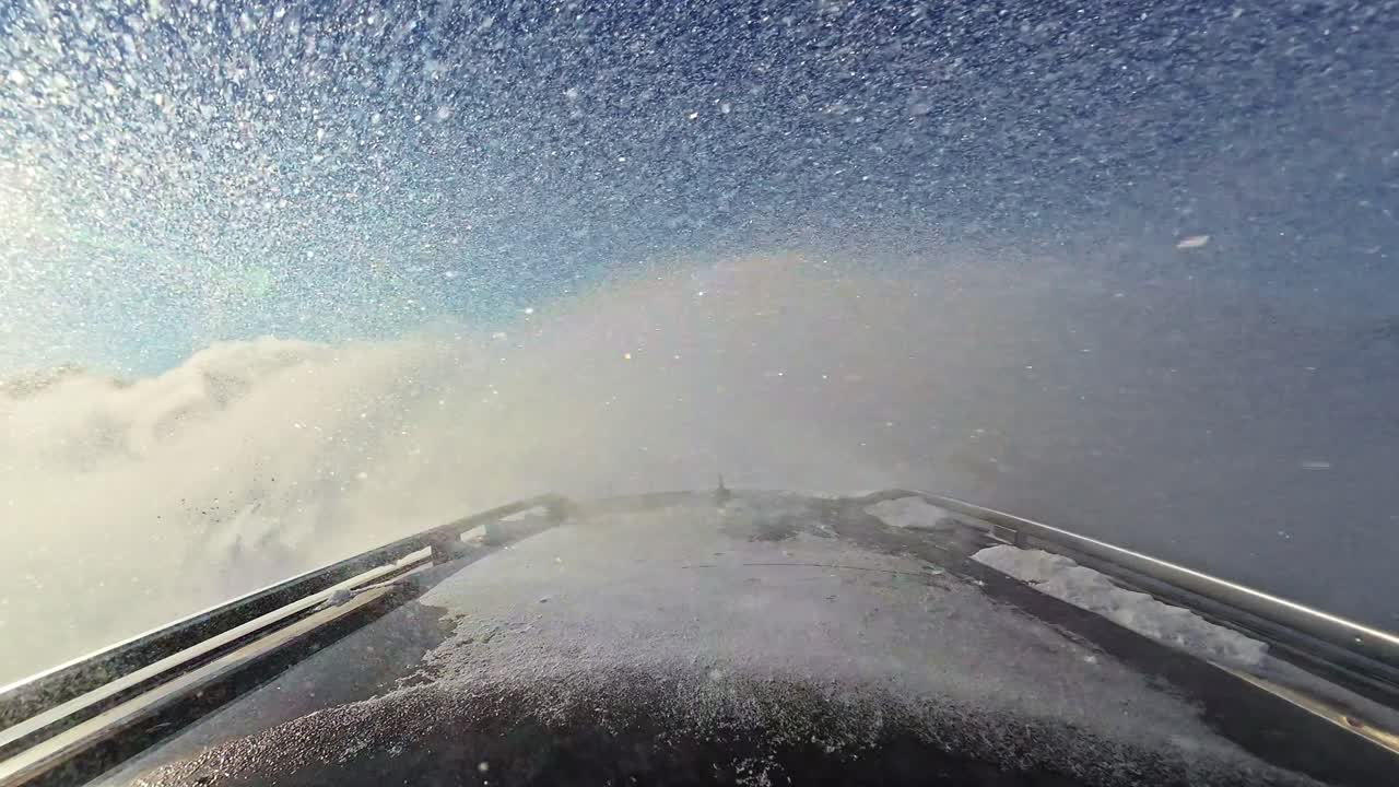 Punto di vista montato sul tetto che guarda all'indietro mentre l'auto derapa sulla neve con la polvere che si solleva dietro