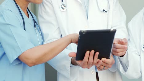 tres médicos discutiendo sobre una tableta digital