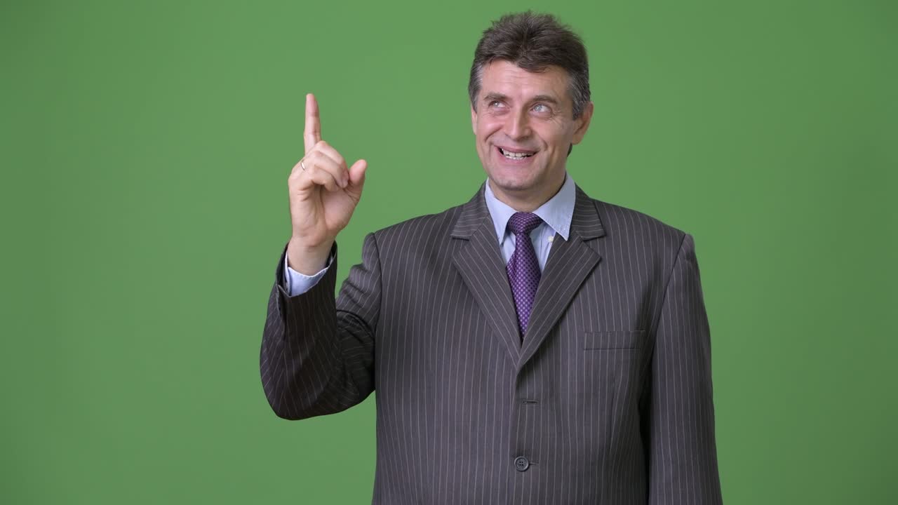 hombre de negocios maduro y guapo contra un fondo verde