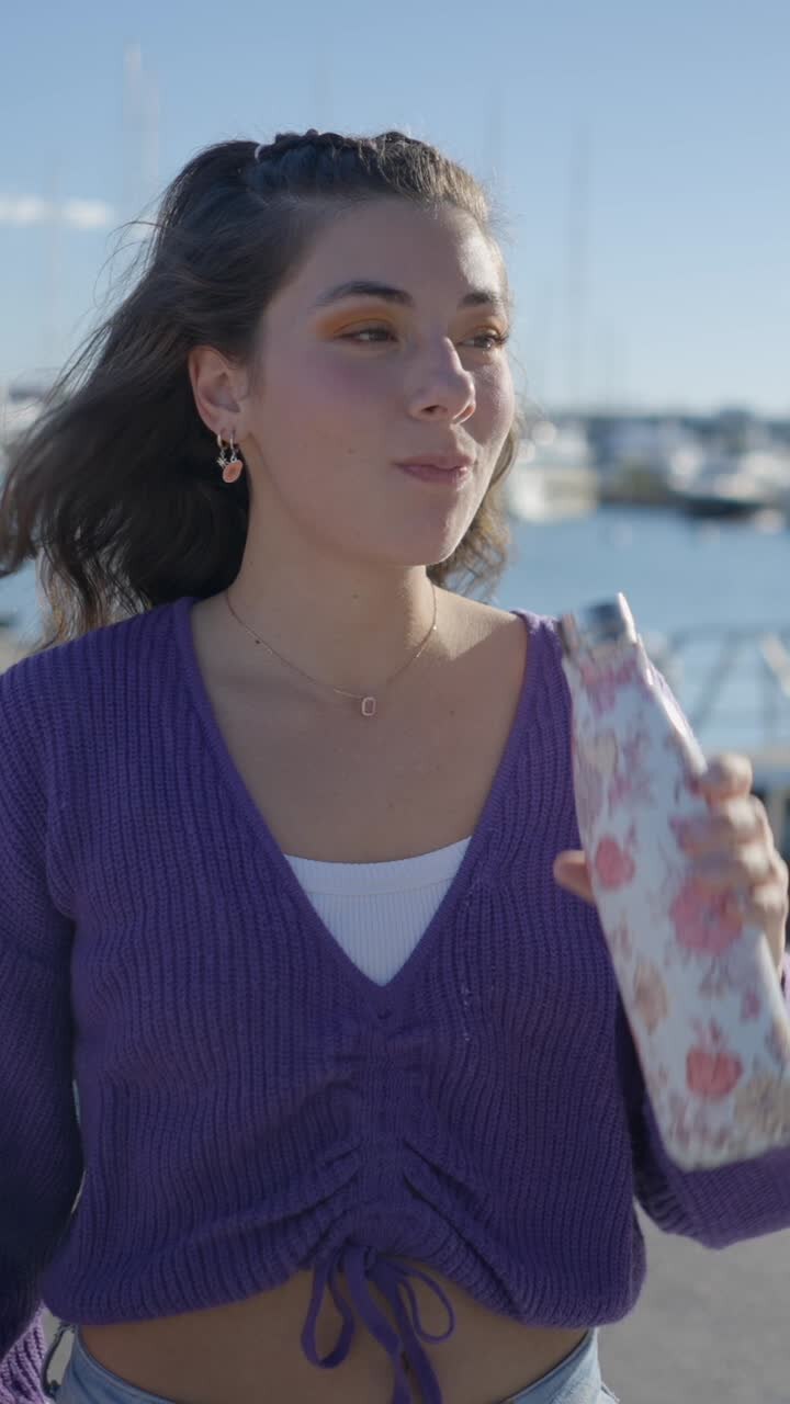 Young Woman Hydrating with a Water Bottle at a Marina