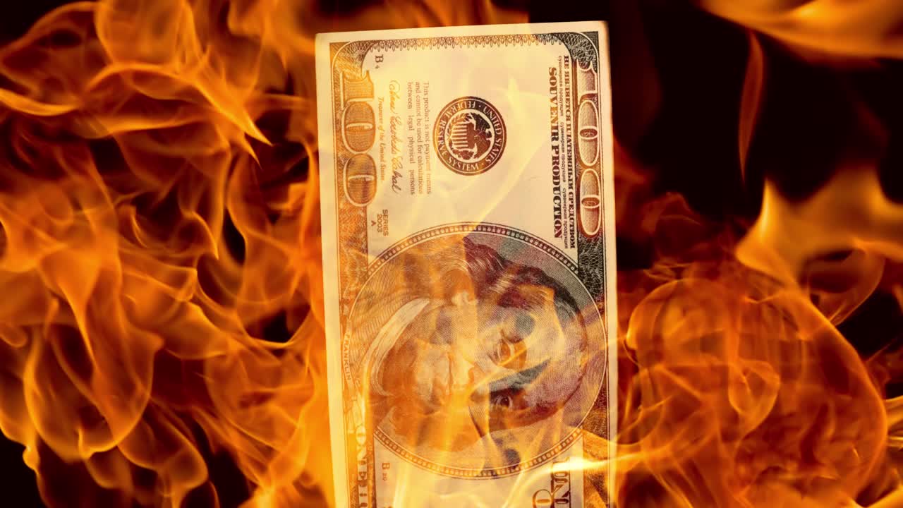 USA dollar bill money is burning in the fire, the concept of the economic crisis of inflation and currency devaluation.