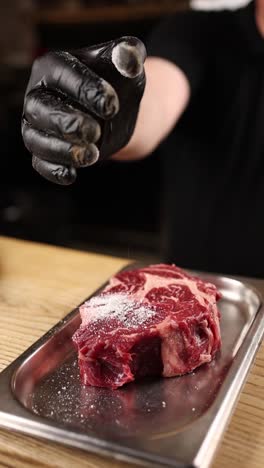 chef seasoning a rib-eye steak