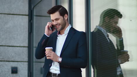 Closeup-businessman-standing-at-street.-Man-smiling-with-phone-in-suit-outside