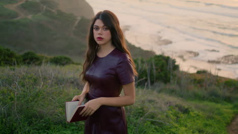 relaxed girl walking slope near ocean holding book closeup. model looking camera