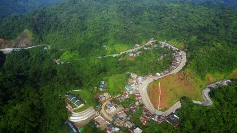 Aerial-static-overview-of-mountain-village-and-winding-road-against-forest