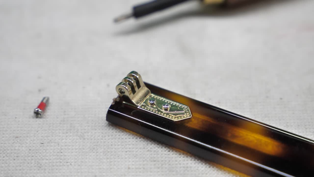 Slow-motion close-up view of endpieces on a glasses frame in a spectacle factory, Danyang, Jiangsu Province, China.