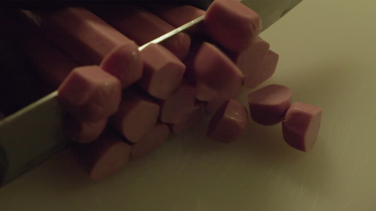 vista de cerca: salchichas de carne procesadas cortadas en pedazos en una tabla de cortar