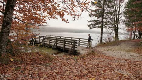 a person walking onto a wooden pier early in the morning during the fall season