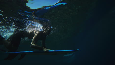 Mittlere-Seitenansicht-Eines-Surfers,-Der-Die-Schienen-Des-Bretts-Hält,-Während-Er-Unter-Einer-Kraftvollen-Brechenden-Welle-Abtaucht