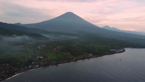 vista aérea amed bali indonesia pequeño pueblo de pescadores en el océano con volcán de monte activo durante la colorida puesta de sol