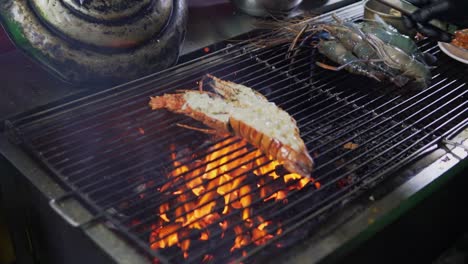 chef cooking a juicy, big, jumbo river prawn over a charcoal grill