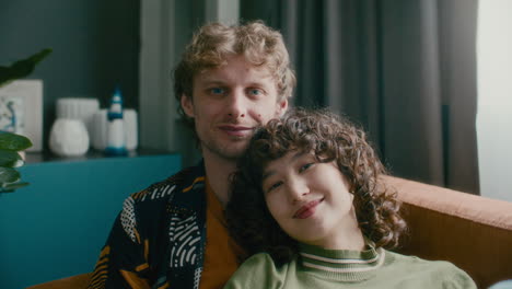 portrait of young smiling couple relaxing together on couch at home