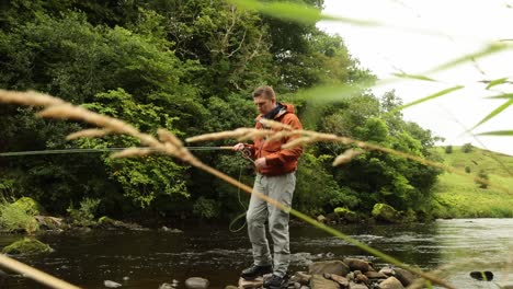 Hand-held-shot-of-a-fly-fisherman-casting-into-the-river-trying-to-catch-trout