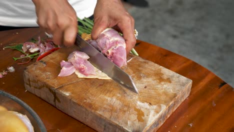 chef cutting chicken wing on wooden table for tom kha kai soup