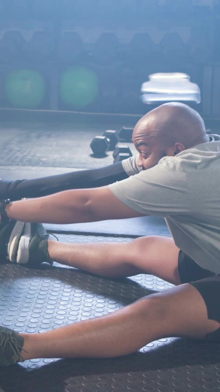 Video vertikal: Pria berkaos lengan pendek di sebelah kanan menarik sesuai isyarat sambil memegang tangan teman di matras gym untuk meregangkan.