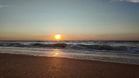 Wellen-Plätschern-Sanft-Ans-Ufer,-Während-Die-Sonne-Untergeht,-Leuchtende-Farben-über-Den-Himmel-Werfen-Und-Sich-Im-Ruhigen-Wasser-Des-Asowschen-Meeres-Spiegeln