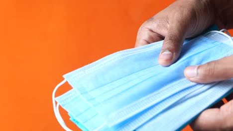 person holding a stack of blue surgical masks