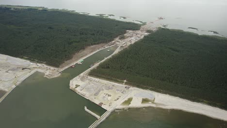 órbita aérea de gran altitud sobre el enorme sitio de construcción del canal del mar y la arquitectura circundante - vía fluvial de infraestructura a una terminal de buques portacontenedores recientemente establecida
