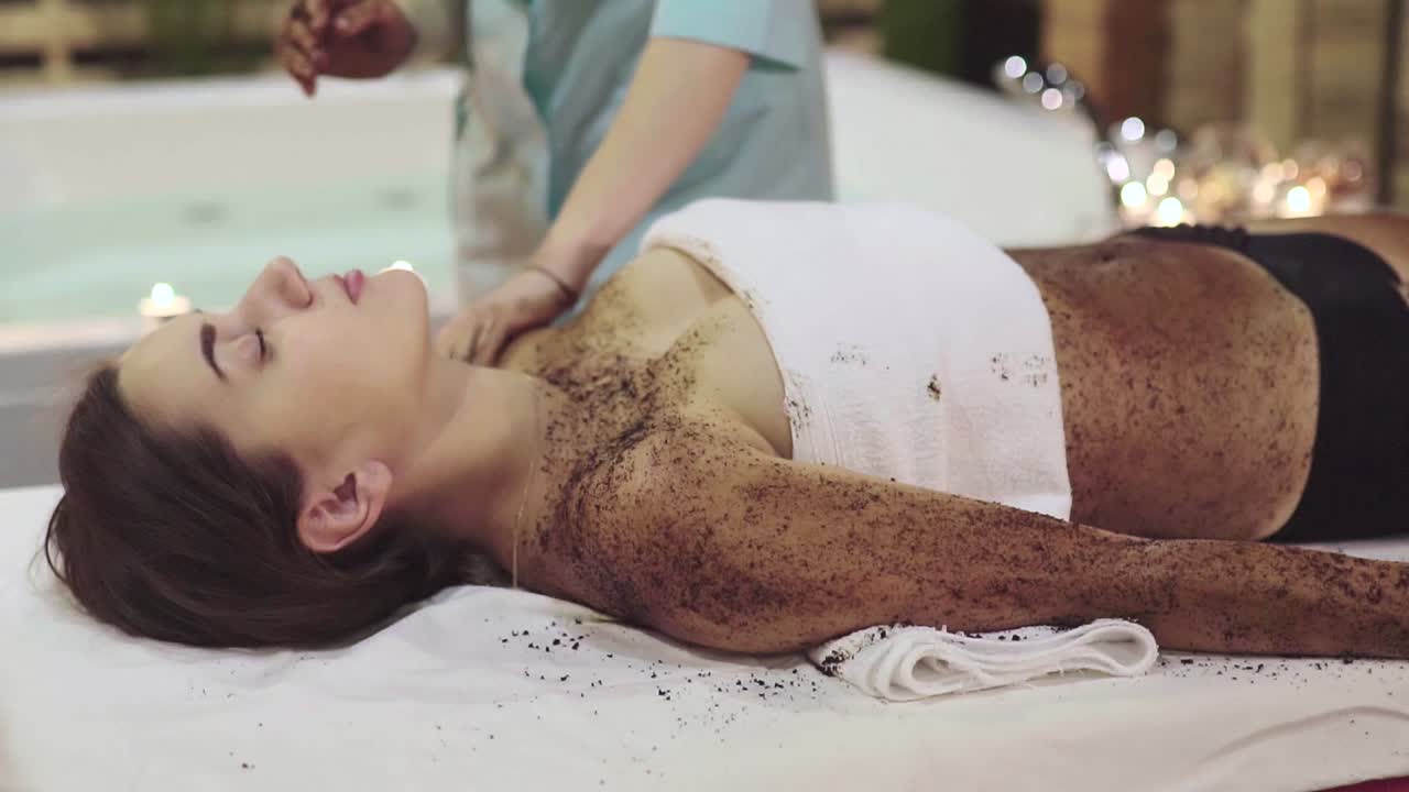 Woman receiving a coffee scrub spa treatment