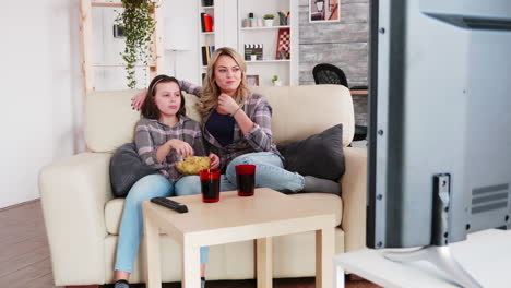 madre feliz y su pequeña hija sentadas en el sofá