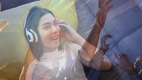 Animation-of-people-dancing-and-biracial-woman-listening-to-music-with-headphones
