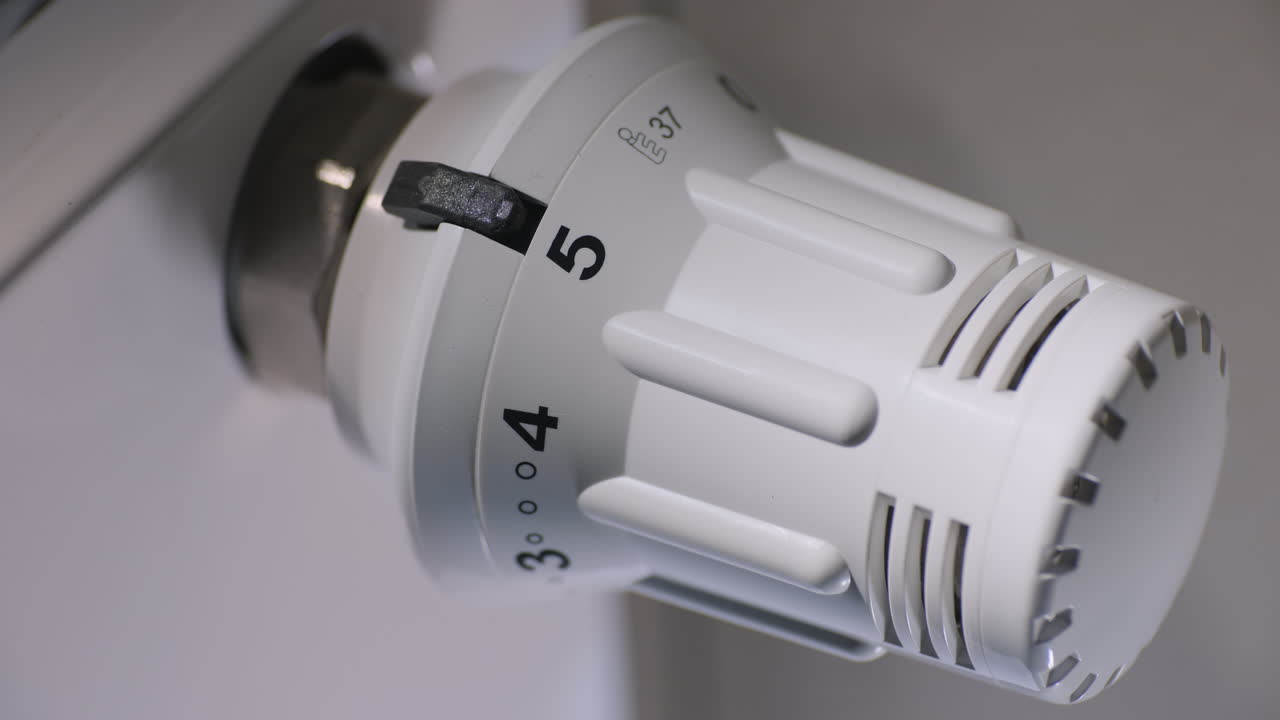 el dueño de casa ajusta la temperatura en la casa en un termostato