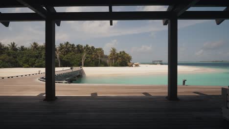 Slow-push-in-shot-of-an-exotic-empty-maldivian-beach-on-a-private-island-shot-from-luxury-hotel-resort-with-blue-turquoise-ocean
