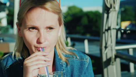 Eine-Frau-Trinkt-Einen-Cocktail-Aus-Einem-Strohhalm-Entspannen-Sie-Sich-Auf-Der-Sommerterrasse-Im-Café-4k-Video