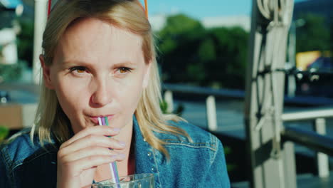 a woman drinks a cocktail from a straw relax on the summer terrace in the cafe 4k video