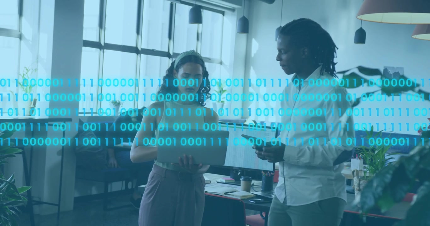Tech team reviewing data tapping laptop and swiping tablet starting binary code overlay over desks