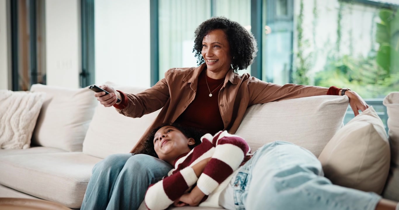 Mother and Daughter Relaxing on Sofa Watching Television at Home