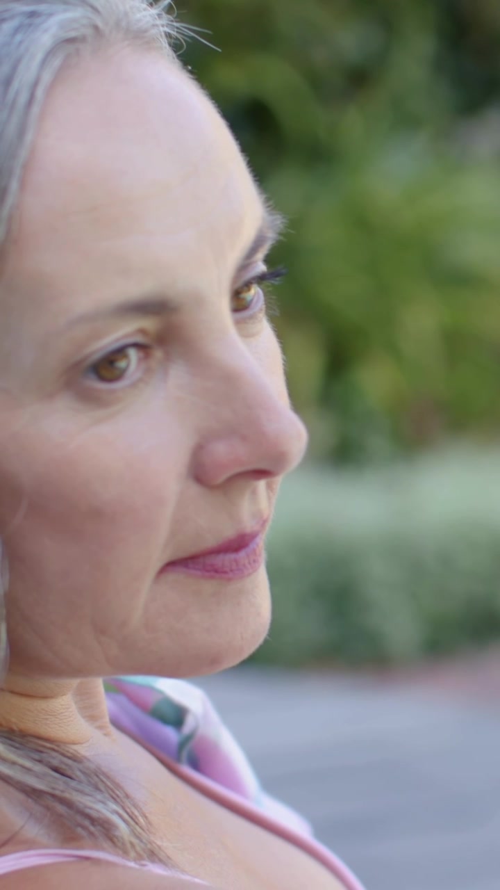 Video verticale: Aprendo gli occhi, una donna con una maglietta a righe gira la testa verso la telecamera in giardino, con spazio per il testo