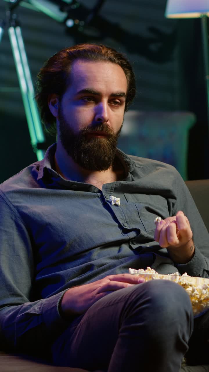 Vertical video Sleepy man watching shows on TV late at night before going to sleep