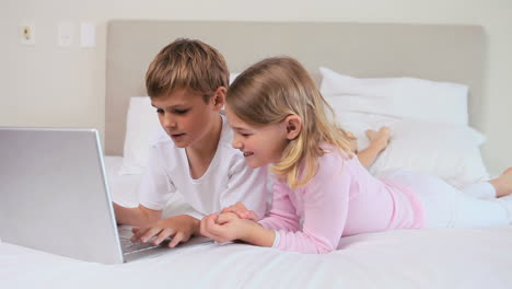 hermanos sonrientes usando una computadora portátil