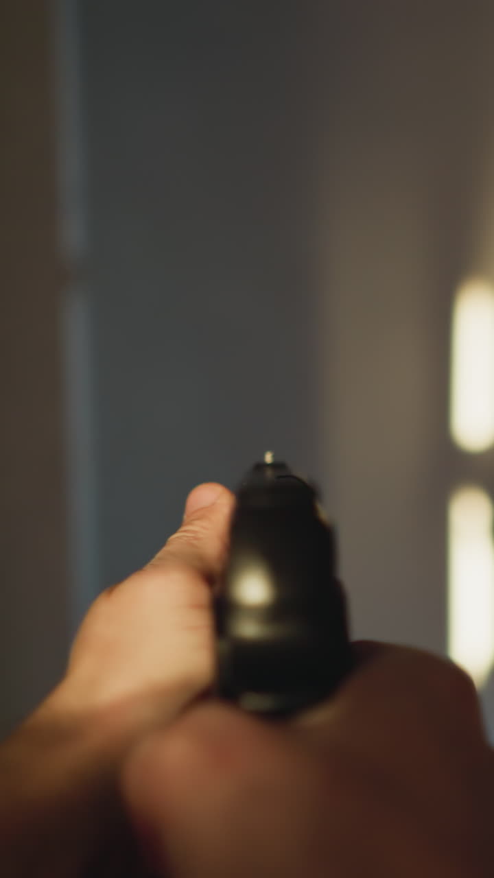 POV footage of a person with a handgun in hand casting a shadow on the wall while cautiously moving down a hallway