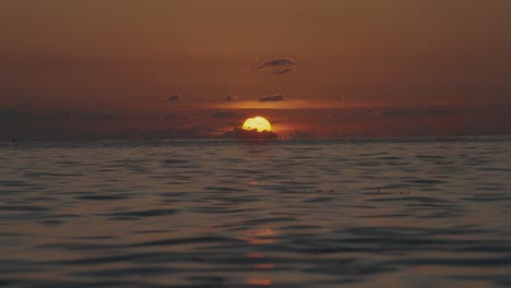 golden hour big round yellow sunset with clouds slow-motion gentle ocean waves in the caribbean