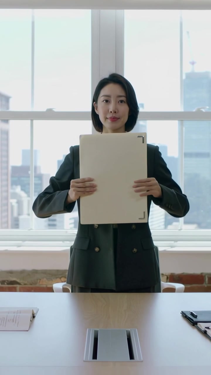 Vertical video: Holding portfolio, woman rotating, centering and showing it in meeting room in suit