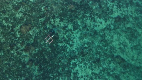 A-lone-bamboo-raft-floating-on-the-clear-turquoise-waters-of-bohol,-philippines,-aerial-view